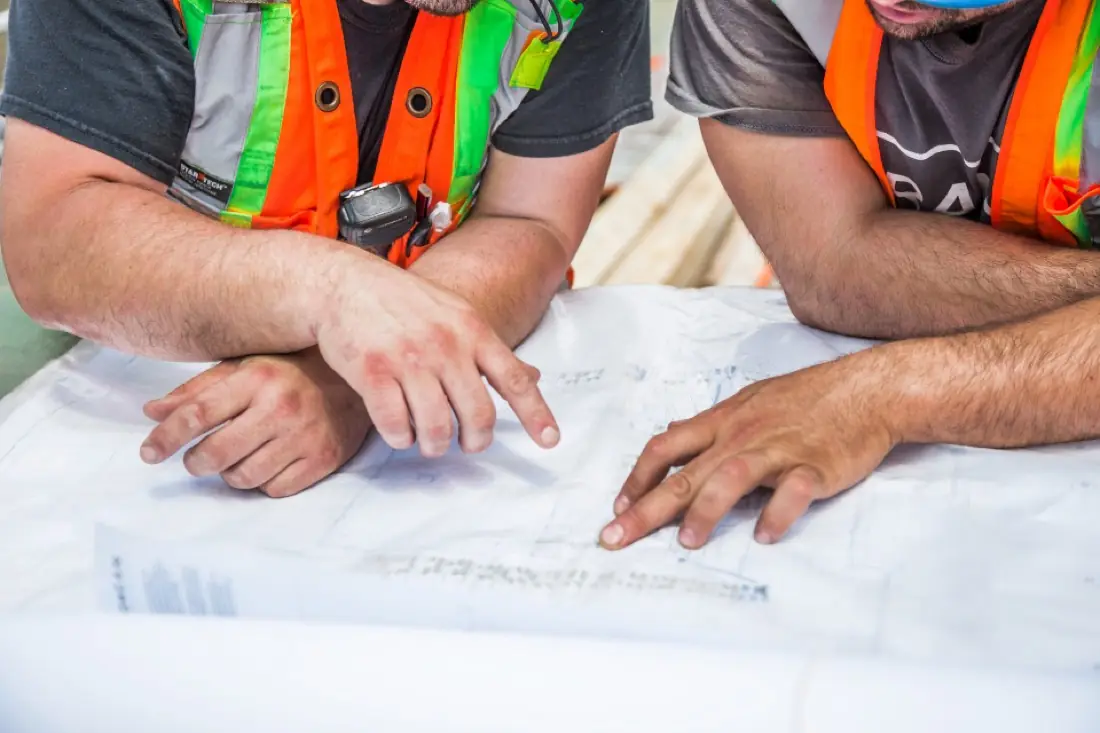 Engineers in safety vests reviewing construction plans