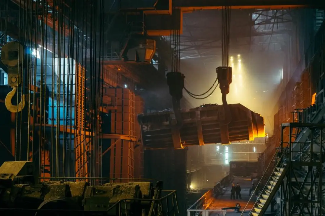 Heavy steel plant with overhead crane and molten metal glow